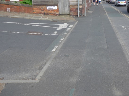 Photo showing transition between side road carriageway and drivable space is flush.