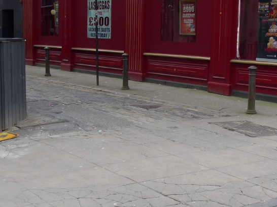 Photo looking into lane. The surface is rough. There is no ramp.