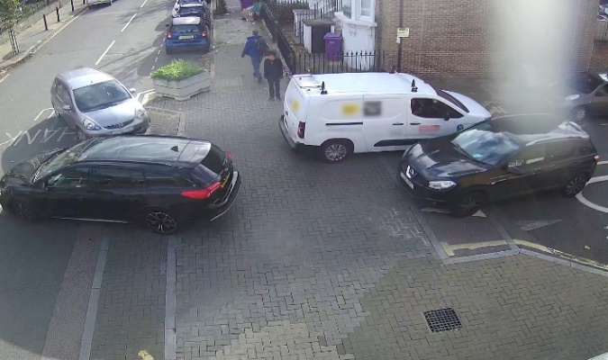 Two vehicles exiting and two vehicles entering the end of Alderney Street. A pedestrian is waiting for these vehicles to clear the site before they attempt to cross.