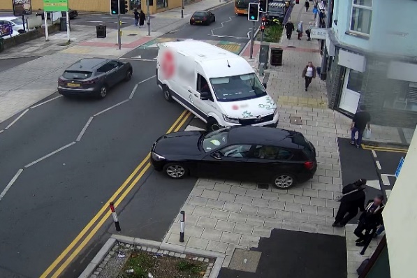 A car exiting Glamorgan Street, while a Transit size van is entering. The van is short of space. There are several pedestrians present, one being ahead of the van. It appears that the van will be driven partly onto the pavement of Glamorgan Street.