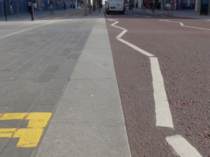 A level surface, lacking a ramp, between the main road carriageway and the drivable space at Scott Street.